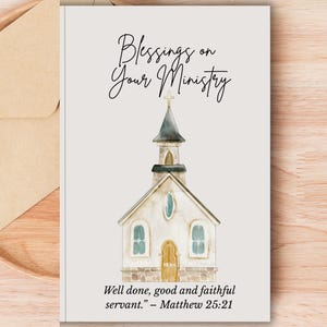Op de afbeelding: Een wenskaart met een aquarel illustratie van een kerk. De kaart bevat de tekst "Blessings on Your Ministry" en een citaat uit Mattheüs 25:21. De kaart ligt op een houten oppervlak met een beige envelop.