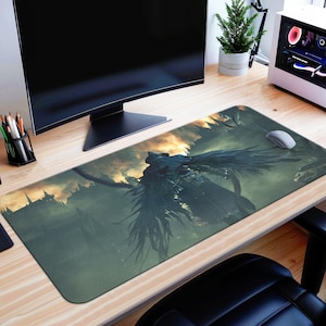 May include: A long, rectangular mouse mat with a dark fantasy illustration of a winged creature against a backdrop of a castle and a fiery sky. The mouse mat is on a wooden desk with a computer monitor, mouse, and other accessories.
