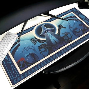 May include: A rectangular blue and cream mousepad with a fantasy illustration. The artwork features a wizard's hat, a dragon, and other figures against a starry night sky. A white keyboard and black monitor are visible.