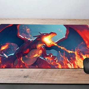 May include: Rectangular mousepad featuring a red and orange dragon breathing fire. The dragon has large blue wings and is set against a fiery background. A black computer mouse is on the right side of the mousepad. The mousepad is on a wooden surface.