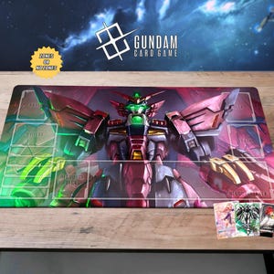 May include: A Gundam card game playmat featuring a detailed illustration of a red and purple mech with green accents. The mat includes designated zones for gameplay and the text "Gundam Card Game".