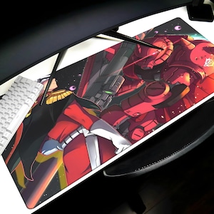 May include: A rectangular mousepad featuring a vibrant anime-style illustration of a red robot and a character in a black and red uniform. The design includes a space-themed background and is set on a white desk with a keyboard.