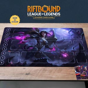 以下が含まれることがあります： 「Riftbound League of Legends Trading Card Game」の長方形プレイマット。紫と青の女性キャラクターのイラストが描かれています。マットには番号付きのゾーンと「ZONES OR NOZONES」の文字があります。2枚のトレーディングカードが見えます。