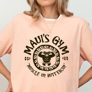 a woman wearing a pink shirt with the words mau's gun on it