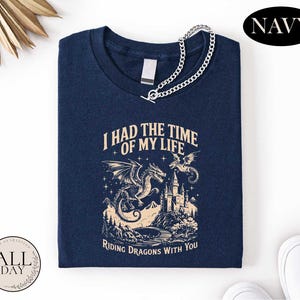 a navy blue t-shirt with a graphic design depicting a castle, a dragon, and mountains, along with the text "I HAD THE TIME OF MY LIFE" and "RIDING DRAGONSLIES WITH YOU".