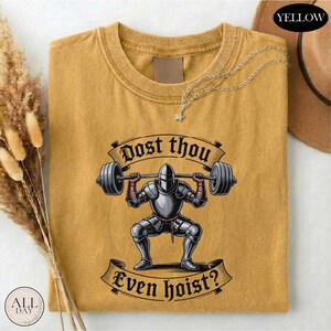 a yellow t-shirt with a graphic design depicting a knight lifting a barbell, accompanied by the text "Dost thou even hoist?"
