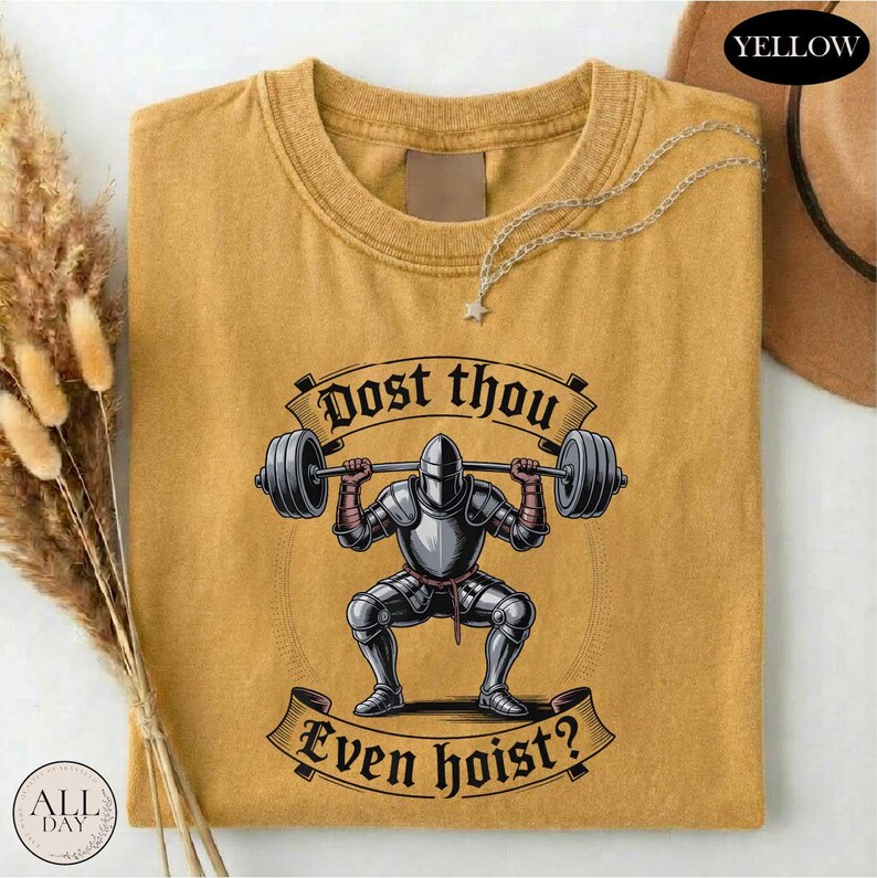 a yellow t-shirt with a graphic design depicting a knight lifting a barbell, accompanied by the text "Dost thou even hoist?"