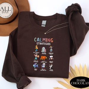 a brown sweatshirt with a colorful graphic design on it, along with a hat and some decorative elements.