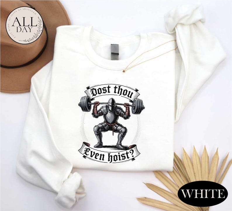 a white long-sleeved shirt with a graphic design depicting a knight lifting a barbell, accompanied by the text "Post thou Even hoist?"