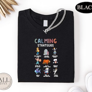 a black t-shirt with a colorful graphic design of various cartoon characters and text, along with a chain.
