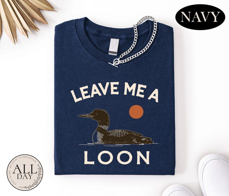 a navy blue t-shirt with a graphic design of a duck and the text "LEAVE ME A LON" printed on it.