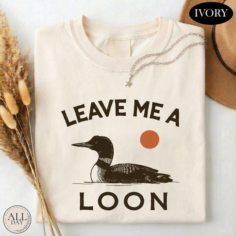 a white t-shirt with a graphic design of a duck and the text "LEAVE ME A LON" printed on it.