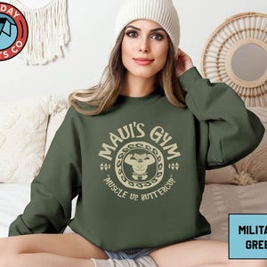 a woman sitting on a bed wearing a green sweatshirt
