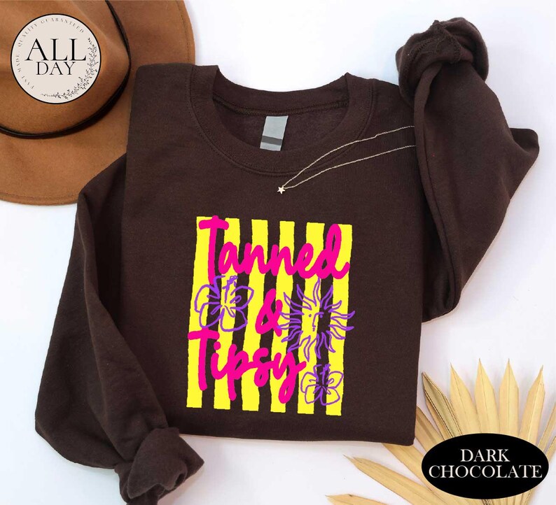 a brown t-shirt with a graphic design, a brown hat, and some decorative leaves, all placed on a white background.