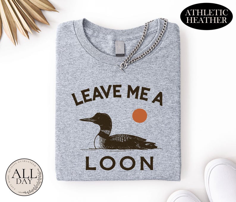 a gray t-shirt with a graphic design of a duck and the text "LEAVE ME A LON" printed on it.