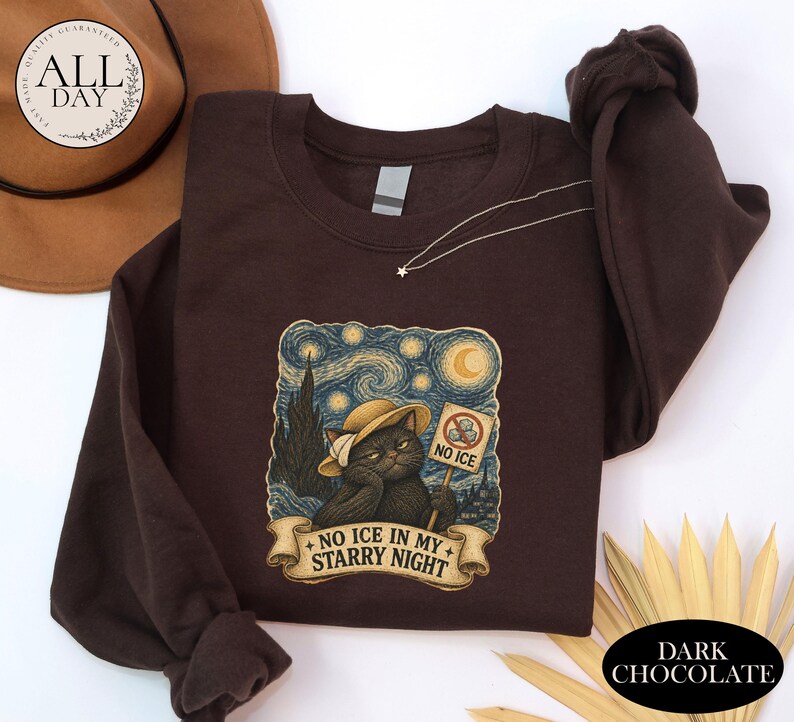 May include: A dark chocolate brown long-sleeve sweatshirt featuring a graphic print of a cat wearing a hat, holding a sign that says NO ICE, with the text NO ICE IN MY STARRY NIGHT on a banner below, set against a swirling starry night background.