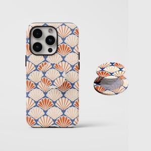 Puede incluir: Una funda de teléfono y un agarre a juego con un patrón de conchas marinas repetido en crema, naranja y azul. La funda está diseñada para un teléfono inteligente y el agarre está adherido a la parte posterior.