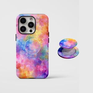 Puede incluir: Una funda de teléfono y un soporte a juego con un diseño de acuarela colorido. La funda está diseñada para un teléfono inteligente y presenta un diseño vibrante en tonos rosa, amarillo, azul y naranja. El soporte para teléfono tiene un diseño similar.