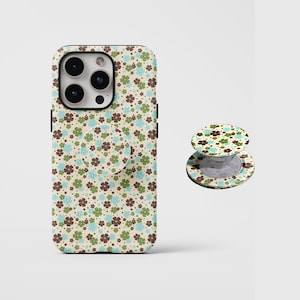 May include: A phone case and matching phone grip featuring a floral pattern in brown, blue, and green on a cream background. The phone case has a camera cutout and the grip is extended. The design is repeated on both items.