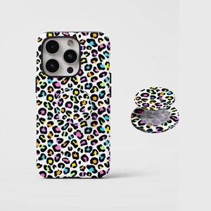 May include: A smartphone case and a matching circular phone grip featuring a white background with a vibrant, multi-colored leopard print pattern in shades of neon pink, blue, yellow, and orange, with black outlines throughout the design.