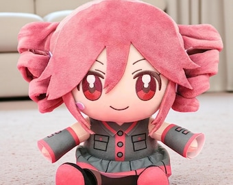 May include: A plush doll featuring a cartoon character with pink hair styled in two side buns. The doll has large red eyes, a gray and pink outfit, and is sitting on a light-colored surface. The doll's arms and legs are also pink.