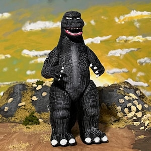 May include: A set of three ceramic mugs with a speckled, matte finish. The mugs are in shades of cream, light gray, and dark gray. Each mug has a simple, minimalist design and a rounded handle.