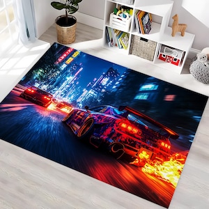May include: A rectangular rug depicting a night-time race scene with cars ablaze with colour, speeding through a city. The rug's design features dynamic movement and bright, illuminated buildings in the background.