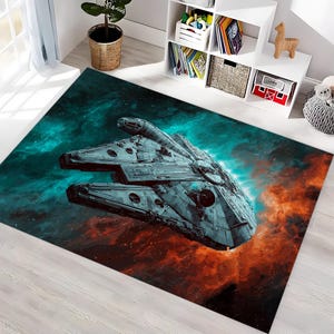 Puede incluir: Alfombra rectangular con una ilustración detallada de una nave espacial sobre un fondo de nebulosa en tonos turquesa, naranja y azul. La alfombra está colocada sobre un suelo de madera clara, creando un contraste llamativo.
