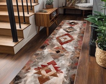 May include: A rectangular area rug with a Southwestern geometric pattern in shades of red, brown, gray, and cream. The rug features diamond and triangle shapes, creating a textured, distressed look. It is placed on a dark wood floor.