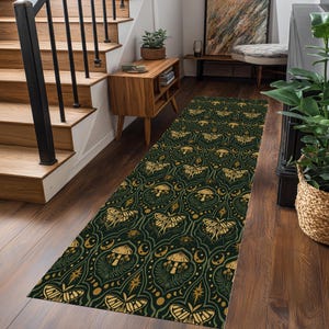 May include: A long, rectangular rug with a dark green background and a repeating pattern of gold-colored moths, mushrooms, and celestial elements. The rug is placed on a wooden floor in a hallway, adding a decorative touch to the space.