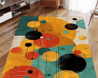 May include: A rectangular area rug with a mid-century modern design. The rug features a pattern of overlapping circles in yellow, orange, black, and teal, with thin black lines. The rug is placed on a hardwood floor.
