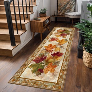 May include: A rectangular runner rug featuring a fall leaf design. The rug displays a cream-colored background with a border and a pattern of red, orange, yellow, and green maple leaves. The rug is placed on a hardwood floor.