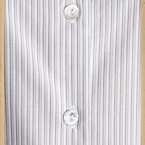 Puede incluir: Una camisa blanca con finas rayas negras y dos botones blancos. La camisa est&aacute; empaquetada en una caja de cart&oacute;n marr&oacute;n con el texto "www.vecona-vintage.com" y "Kleidsames & Stilvolles" impreso en ella.