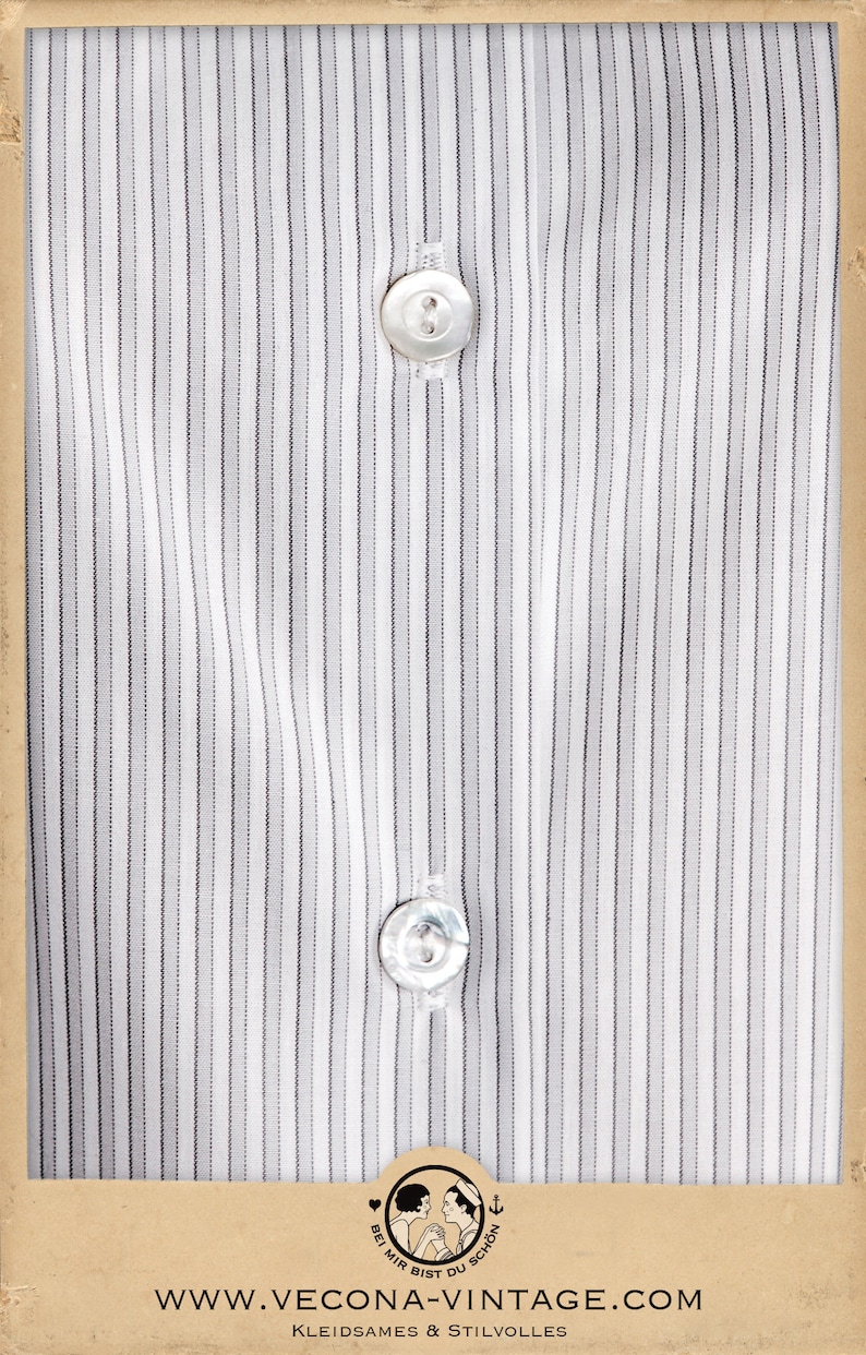 Puede incluir: Una camisa blanca con finas rayas negras y dos botones blancos. La camisa est&aacute; empaquetada en una caja de cart&oacute;n marr&oacute;n con el texto "www.vecona-vintage.com" y "Kleidsames & Stilvolles" impreso en ella.