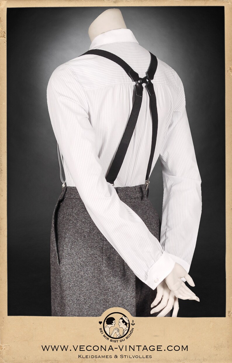 Puede incluir: Tirantes negros con una camisa blanca de botones y pantalones grises. Los tirantes tienen una correa de cuero y clips met&aacute;licos. La camisa tiene un patr&oacute;n a rayas. Los pantalones tienen una tela texturizada.