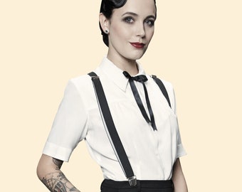 May include: A woman wearing a white button-down shirt with black suspenders and a black bow tie. She has dark hair styled in a vintage updo and is wearing black pants.