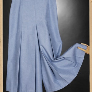 May include: A light blue pleated skirt with a high waist and a wide leg. The skirt is made of a lightweight fabric and has a relaxed fit.