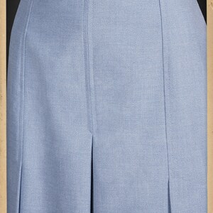 May include: A light blue skirt with pleats and a high waist. The skirt is made of a smooth, textured fabric.
