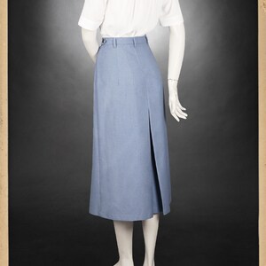May include: A light blue skirt with a front slit and a white button-up shirt. The skirt is knee-length and has a high waist. The shirt has short sleeves and a collar.