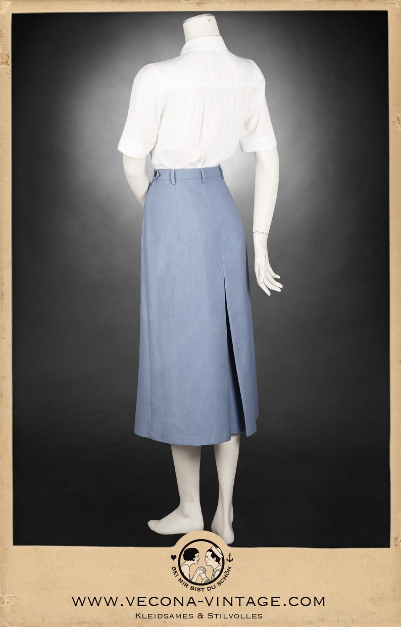 May include: A light blue skirt with a front slit and a white button-up shirt. The skirt is knee-length and has a high waist. The shirt has short sleeves and a collar.