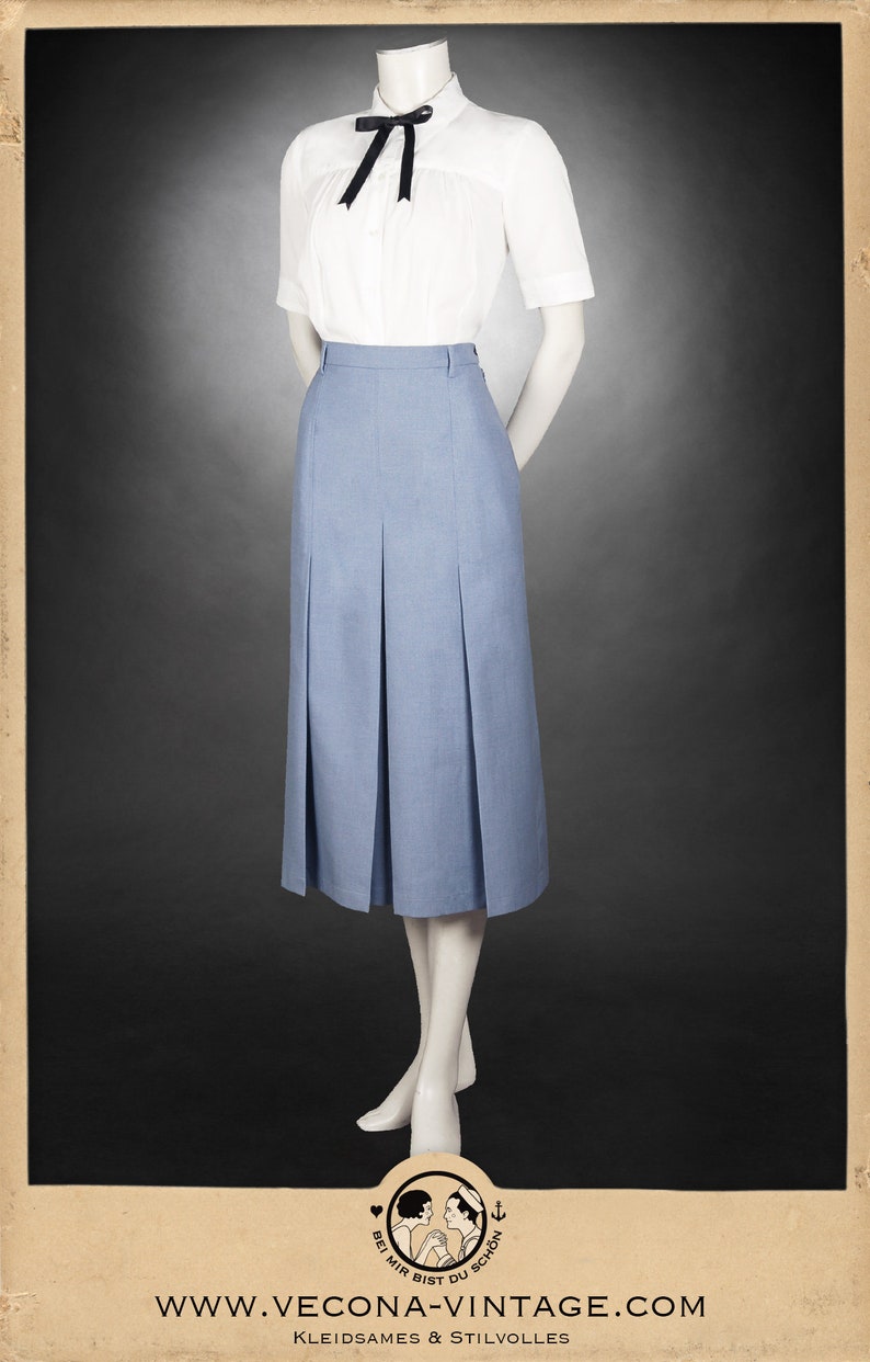 May include: A light blue pleated skirt with a white button-up shirt with a black bow tie. The skirt is knee-length and has a high waist. The shirt has short sleeves and a collar. The model is wearing the outfit on a mannequin.