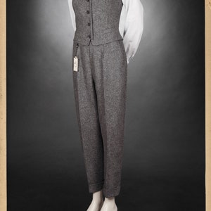 Puede incluir: Un chaleco de tweed gris con una camisa blanca abotonada y una corbata azul. El chaleco tiene cuello en V y seis botones. La camisa tiene un patr&oacute;n a rayas. La corbata tiene un patr&oacute;n de rayas diagonales. El atuendo est&aacute; en un maniqu&iacute;.