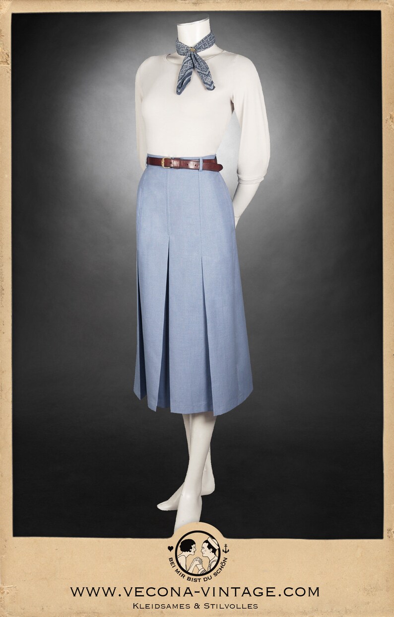 May include: A light blue pleated skirt with a brown belt and a white sweater with a blue patterned scarf. The skirt is knee-length and has a high waist.