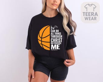 May include: Black t-shirt featuring an orange basketball graphic with the text "I CAN DO ALL THINGS THROUGH CHRIST WHO STRENGTHENS ME" and the Bible verse Philippians 4:13. The shirt has a crew neck and short sleeves.