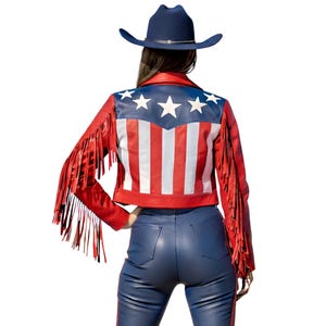 May include: A red leather jacket with fringe and a patriotic design featuring red and white stripes and a blue panel with white stars. The jacket is paired with blue leather pants and a navy cowboy hat.