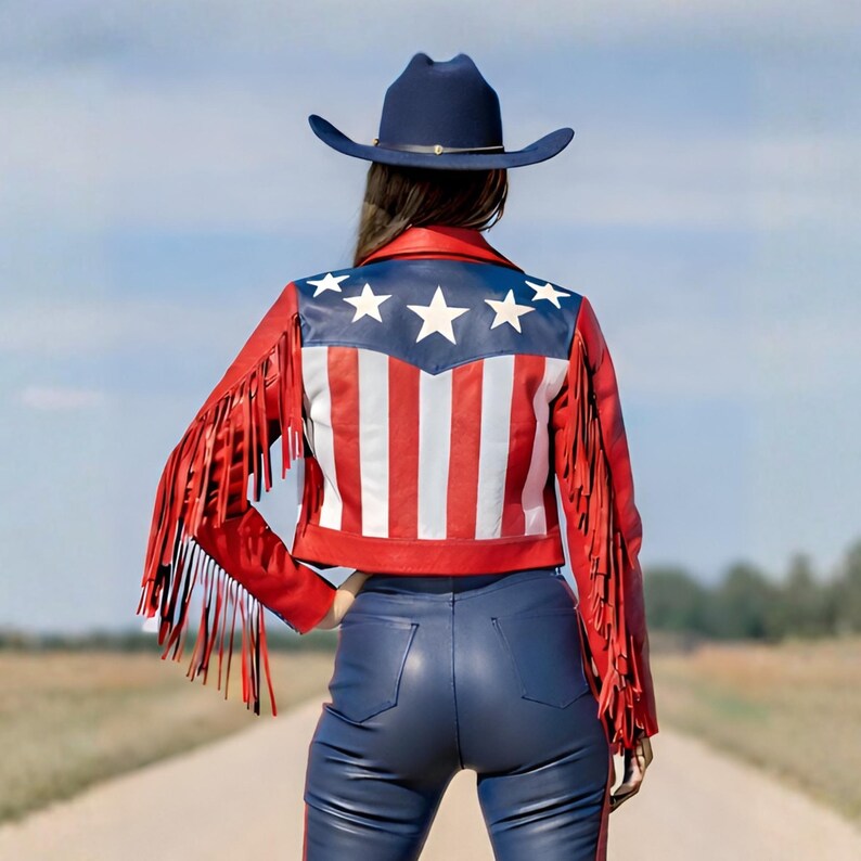 May include: A red leather jacket with white and red stripes and blue stars, paired with blue leather pants and a navy cowboy hat. The jacket features long red fringe on the sleeves, creating a bold, patriotic look.