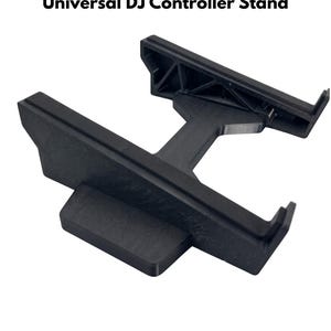 Op de afbeelding: Een zwarte DECKSTAND PRO Universal DJ Controller Stand met een stijf H-vormig frame, twee horizontale steunbalken en een centrale verbindingsstang. De structuur heeft een matte afwerking en verhoogde randen om apparatuur vast te zetten.