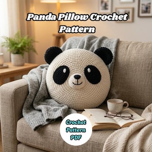 Könnte beinhalten: Ein runder, cremefarbener Panda-Kissen mit schwarzen Ohren und Gesichtszügen liegt auf einer grauen Decke auf einem Sofa. Der Text "Panda Pillow Crochet Pattern" steht oben. Eine Tasse Kaffee und ein Buch mit Brille sind in der Nähe.