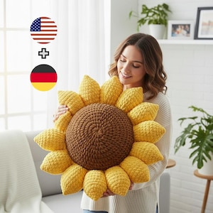 May include: A large, handmade sunflower pillow with a brown center and yellow petals. The pillow is made of a soft, textured material, and is being held by a person. The pillow is a decorative item for a home.