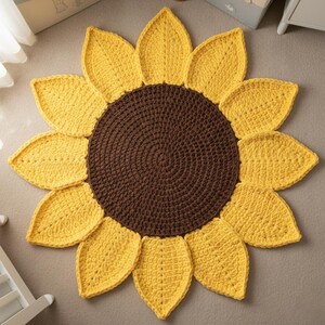 May include: A handmade, crochet sunflower rug with a brown center and yellow petals. The rug is round and has a textured appearance, resembling a real sunflower. This decorative rug is suitable for a child's room or any space needing a touch of nature.